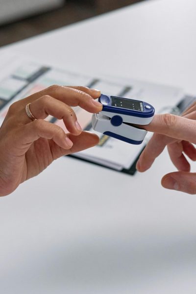 Close-up of a fingertip pulse oximeter being used to measure a patient's heart rate and oxygen levels.